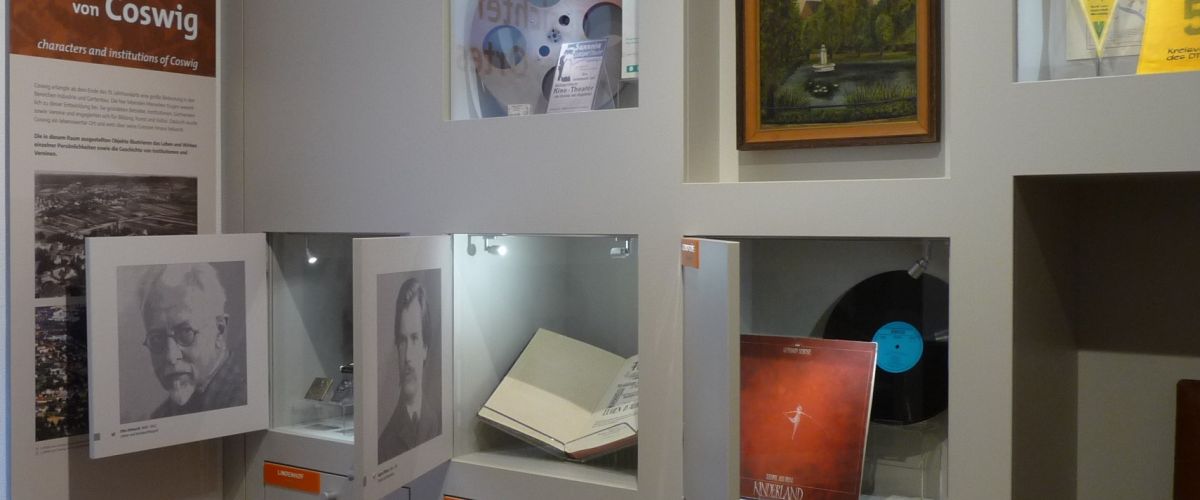 Raum Persönlichkeiten und Institutionen - Blick auf einzelne geöffnete Fächer mit Fotos und Objekten