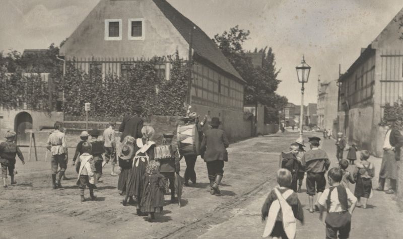 Historische Fotografie der Hauptstraße Coswig mit Kindern, die Musikern folgen