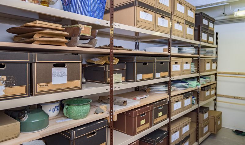 Blick in Magazinraum mit beschrifteten Kartons in Regalen 